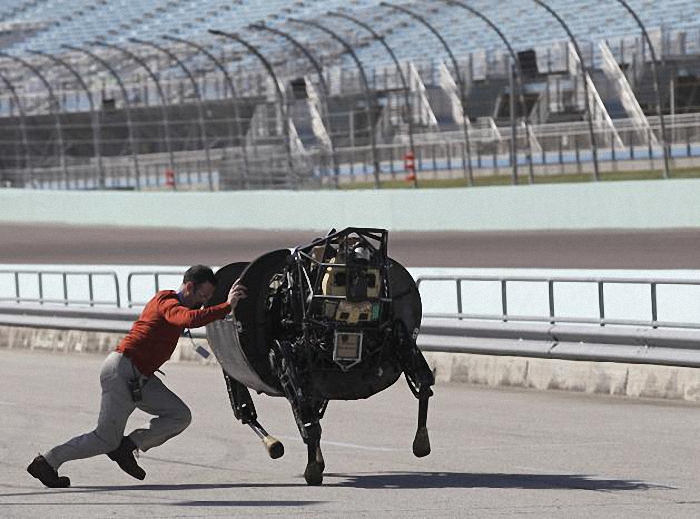 An unidentified LS3 team member shoves an LS 3 (Legged Squad Support System) robot that was galloping off course, back on track during a high-speed demonstration in Homestead, Florida in this December 20, 2013 file photo. Three-fourths of robot installations over the next decade are expected to be concentrated in four areas: transportation equipment, including the automotive sector; computer and electronic products; electrical equipment and machinery. Labor costs have climbed in countries such as China that have been popular for outsourcing production, while technological advances for robots allow them to be more flexible and perform more tasks. REUTERS/Andrew Innerarity/Files ATTENTION EDITORS - THIS PICTURE IS PART OF THE PACKAGE "RISE OF THE MACHINES". TO FIND ALL 20 IMAGES SEARCH 'TECHNOLOGY ROBOTS'.      TPX IMAGES OF THE DAY