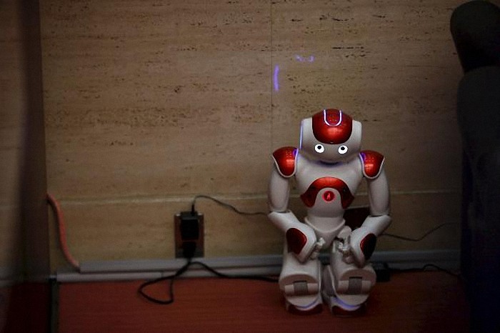 A "Nao" humanoid robot by Aldebaran Robotics sits in a corner while its batteries are being charged during a presentation at a branch of the Bank of Tokyo-Mitsubishi UFJ (MUFG) in Tokyo in this April 13, 2015 file photo. Three-fourths of robot installations over the next decade are expected to be concentrated in four areas: transportation equipment, including the automotive sector; computer and electronic products; electrical equipment and machinery. Labor costs have climbed in countries such as China that have been popular for outsourcing production, while technological advances for robots allow them to be more flexible and perform more tasks. REUTERS/Thomas Peter/Files ATTENTION EDITORS - THIS PICTURE IS PART OF THE PACKAGE "RISE OF THE MACHINES". TO FIND ALL 20 IMAGES SEARCH 'TECHNOLOGY ROBOTS'.      TPX IMAGES OF THE DAY